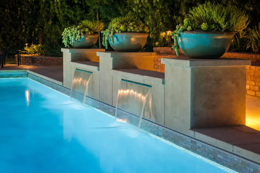 Water spillways and planted bowls under low-voltage lighting at dusk, Muirlands